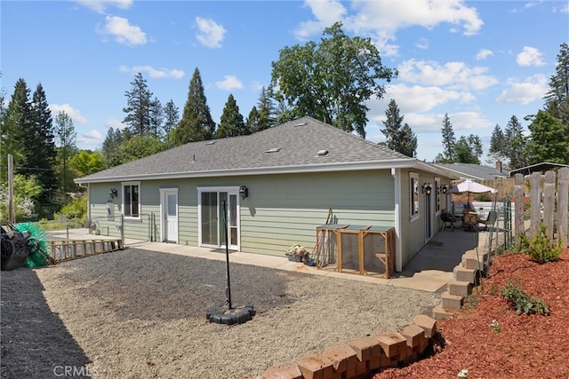 rear view of house featuring fence, roof with shingles, and a patio area