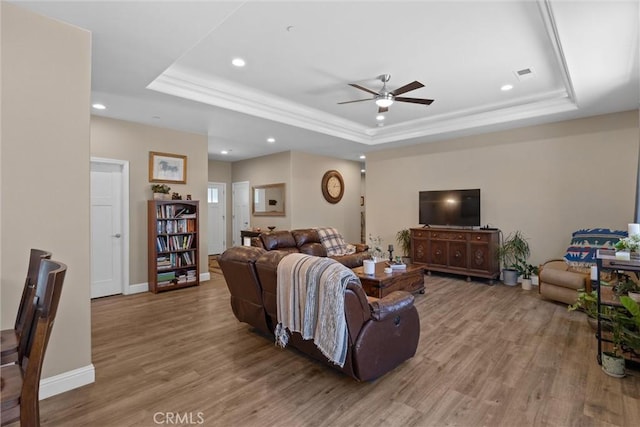 living area with visible vents, ceiling fan, a tray ceiling, recessed lighting, and wood finished floors