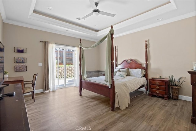 bedroom featuring crown molding, access to exterior, wood finished floors, and a tray ceiling