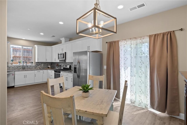 dining room with wood finished floors, visible vents, recessed lighting, and a notable chandelier