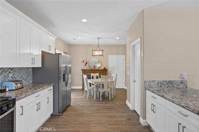kitchen with decorative backsplash, stone counters, light wood-style flooring, baseboards, and white cabinets
