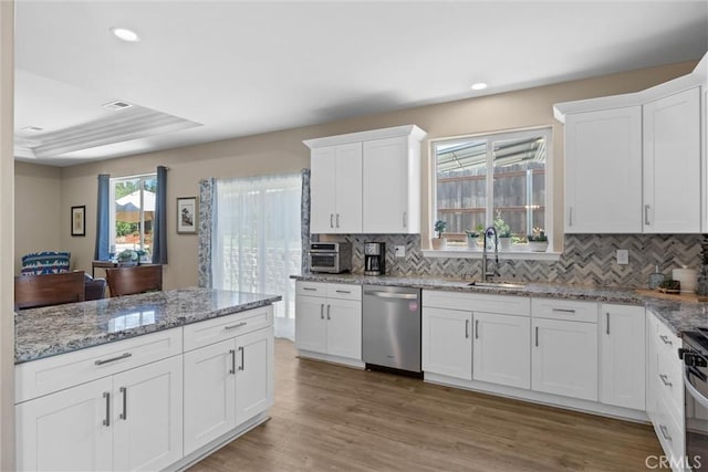 kitchen with a sink, white cabinets, stainless steel appliances, and decorative backsplash