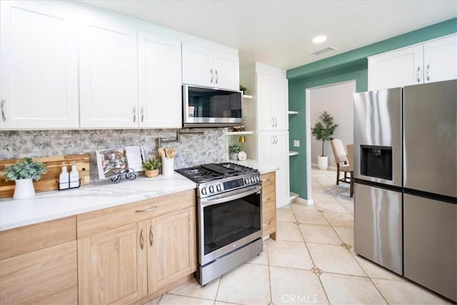 kitchen featuring stainless steel appliances, light tile patterned floors, tasteful backsplash, visible vents, and white cabinetry