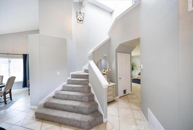staircase with a high ceiling, tile patterned flooring, and baseboards