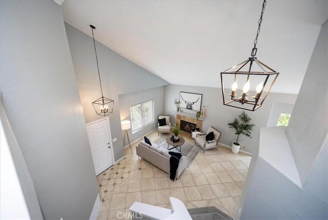 living room with a chandelier, vaulted ceiling, a premium fireplace, baseboards, and light tile patterned flooring