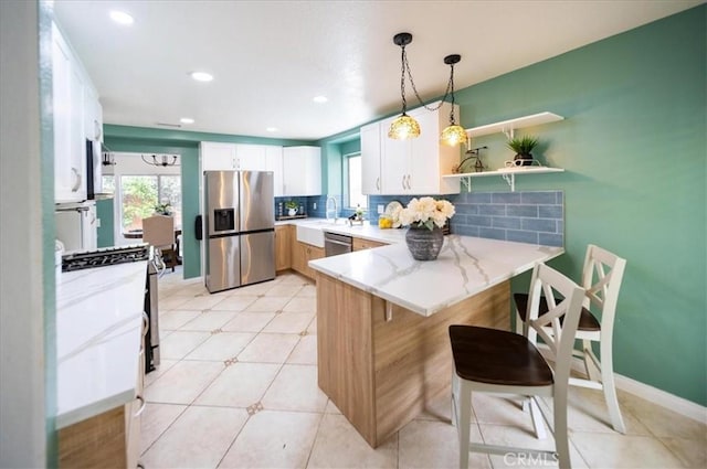 kitchen with appliances with stainless steel finishes, a peninsula, decorative backsplash, and light stone countertops