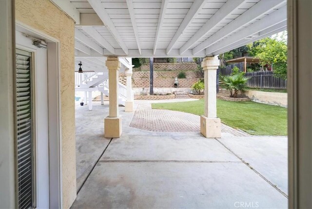 view of patio featuring fence and stairway