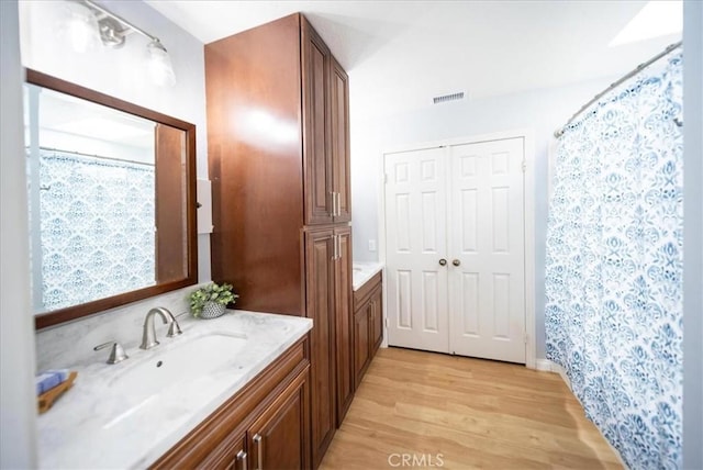 full bathroom featuring curtained shower, vanity, visible vents, and wood finished floors