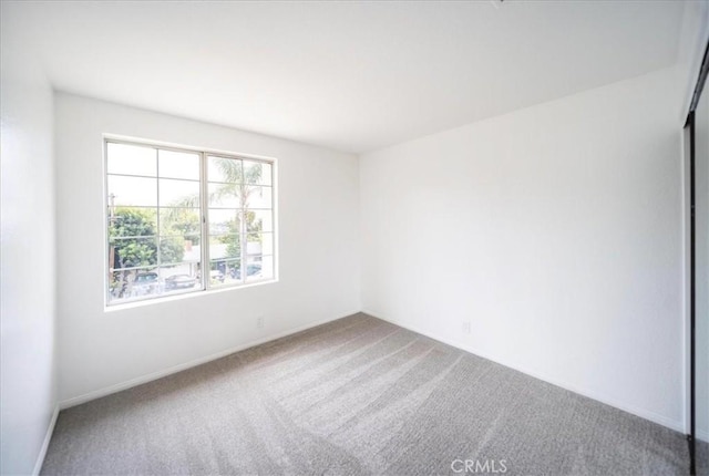carpeted spare room featuring baseboards