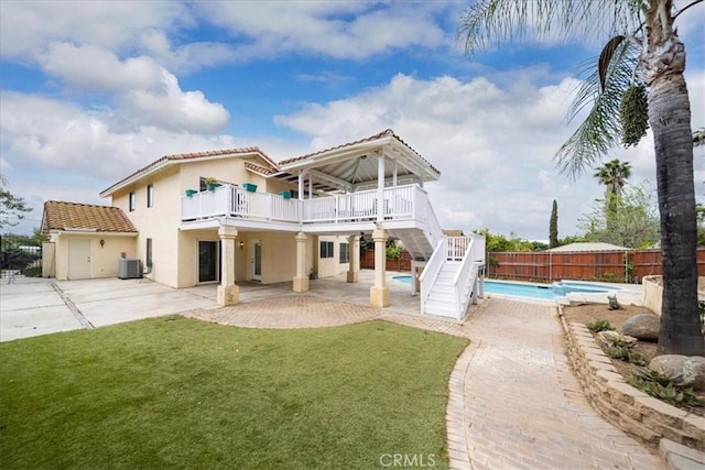 rear view of property with a fenced backyard, stairway, a fenced in pool, a tile roof, and a lawn