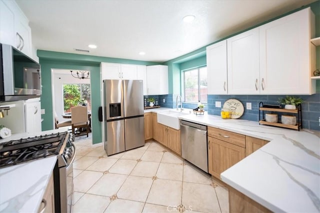 kitchen featuring open shelves, stainless steel appliances, a healthy amount of sunlight, and a sink