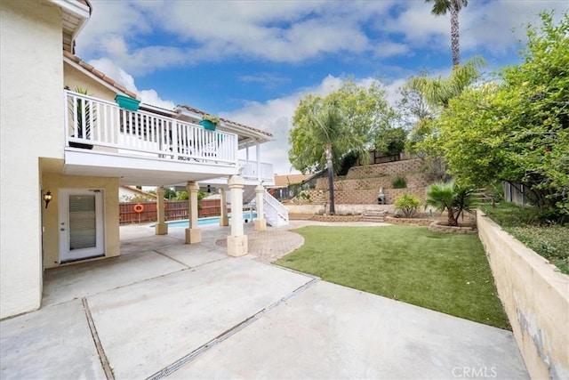 view of yard with a balcony, a fenced in pool, a patio area, fence, and stairway