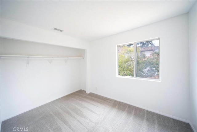 unfurnished bedroom with carpet flooring, a closet, and visible vents