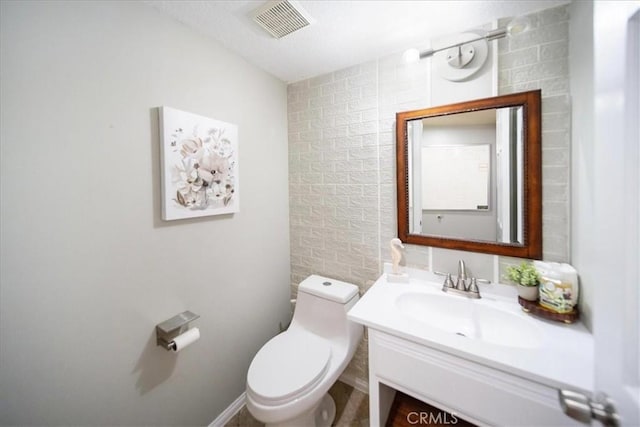 bathroom with toilet, visible vents, and vanity