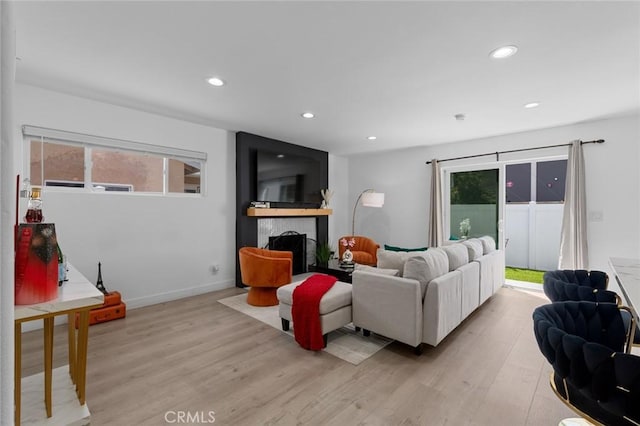 living room with light wood-type flooring, recessed lighting, a fireplace, and plenty of natural light