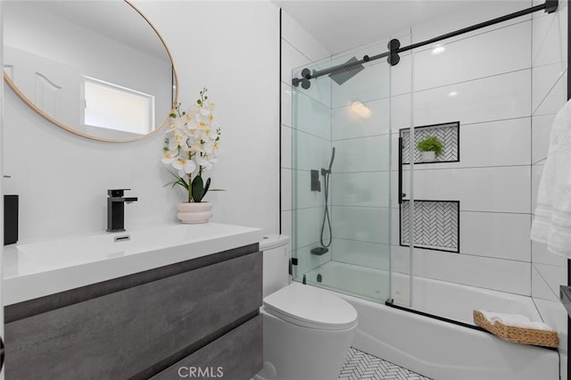 bathroom featuring toilet, bath / shower combo with glass door, and vanity