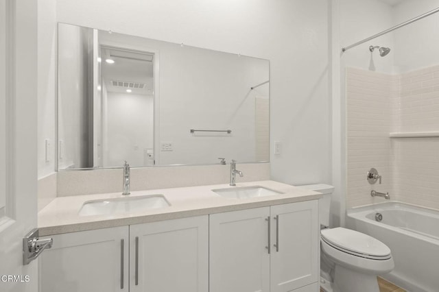 bathroom featuring double vanity, toilet, a sink, and bathtub / shower combination