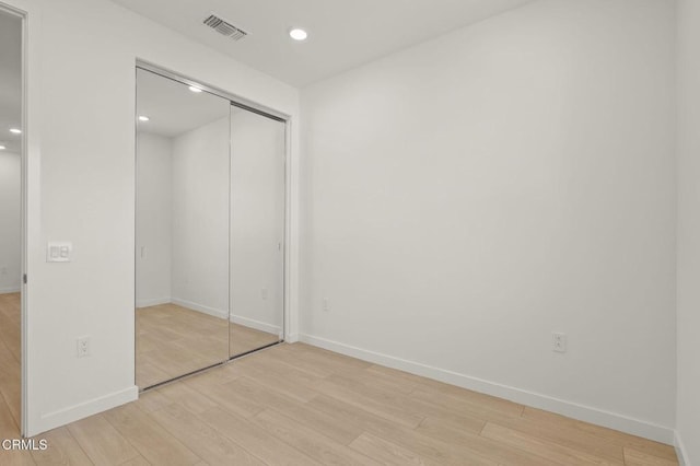 unfurnished bedroom featuring visible vents, a closet, baseboards, recessed lighting, and light wood finished floors