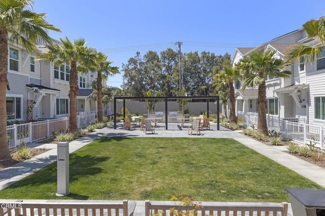 view of property's community featuring a yard, fence, a residential view, and a patio area
