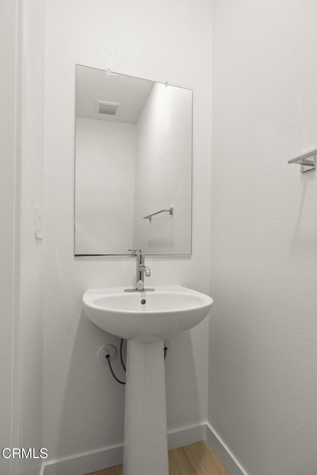 bathroom with baseboards, wood finished floors, and visible vents