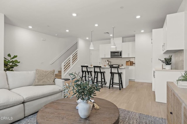 living area with recessed lighting, stairway, and light wood-style floors