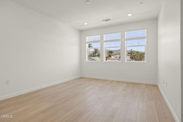 empty room with recessed lighting, baseboards, light wood-type flooring, and visible vents