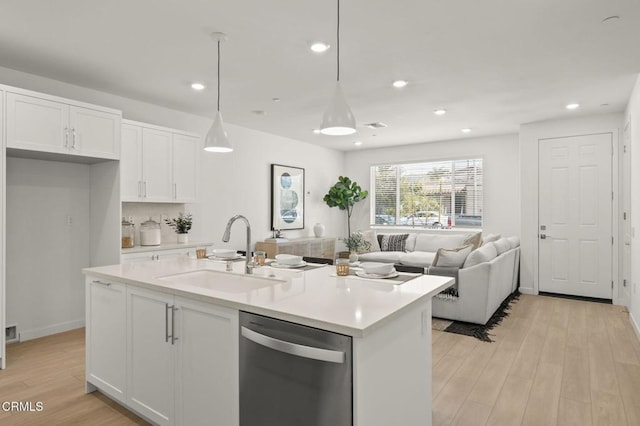 kitchen with a sink, light countertops, white cabinetry, light wood-type flooring, and stainless steel dishwasher
