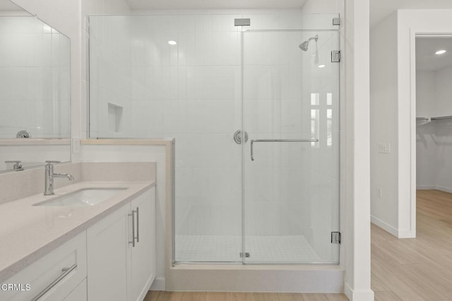 bathroom with baseboards, a shower stall, wood finished floors, and vanity