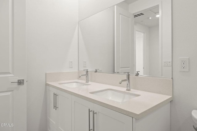 bathroom with double vanity, toilet, visible vents, and a sink