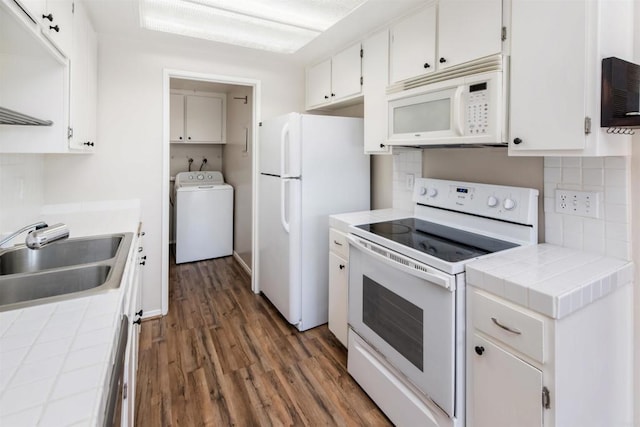 kitchen with washer / clothes dryer, a sink, tile counters, dark wood finished floors, and white appliances