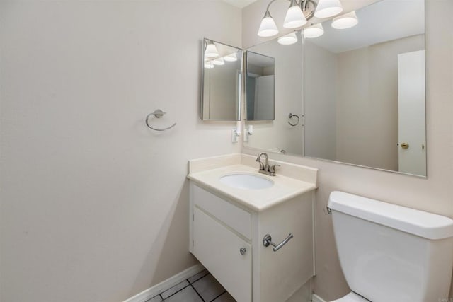 half bathroom with tile patterned floors, a notable chandelier, toilet, and vanity