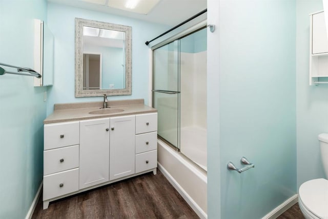 full bathroom featuring vanity, bath / shower combo with glass door, toilet, baseboards, and wood finished floors