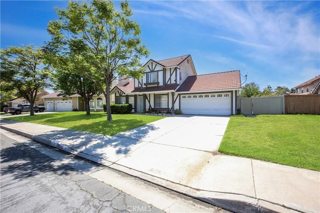 english style home featuring a tiled roof, a garage, fence, a front lawn, and concrete driveway