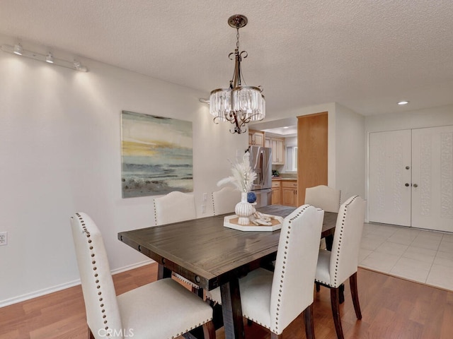 2390 Via Mariposa W Unit 2E, Laguna Woods, CA 92637 - dining space featuring a textured ceiling, a notable chandelier, light wood-style flooring, and baseboards