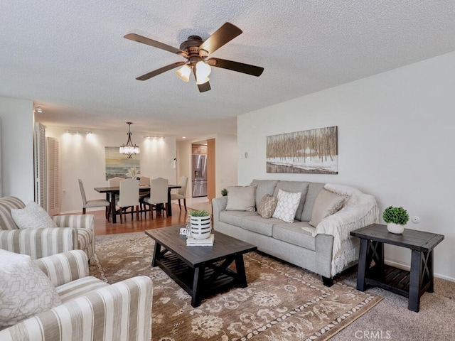 2390 Via Mariposa W Unit 2E, Laguna Woods, CA 92637 - living room featuring baseboards, ceiling fan with notable chandelier, and a textured ceiling