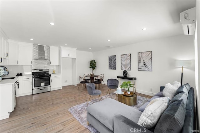 11445 Saticoy St, North Hollywood, CA 91605 - living room featuring light wood finished floors, a wall mounted air conditioner, baseboards, and recessed lighting