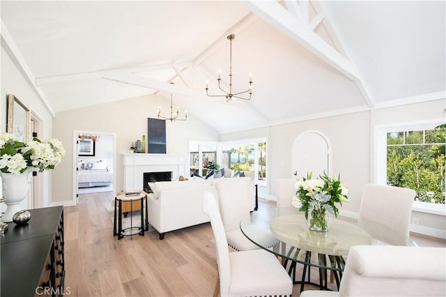 567 Flora St, Laguna Beach, CA 92651 - dining room with baseboards, light wood finished floors, a fireplace, a notable chandelier, and vaulted ceiling with beams