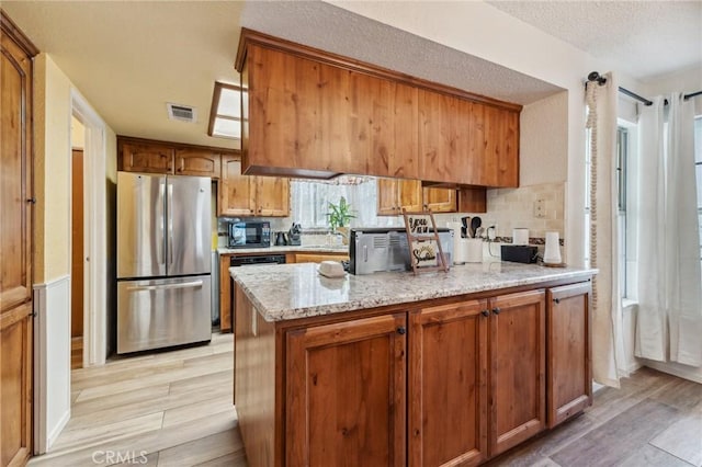 1045 Clover Ln, Hanford, CA 93230 - kitchen featuring freestanding refrigerator, light wood-type flooring, black microwave, brown cabinets, and decorative backsplash