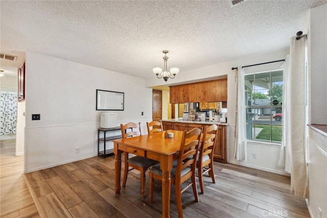 1045 Clover Ln, Hanford, CA 93230 - dining area with light wood-type flooring, a chandelier, and a textured ceiling