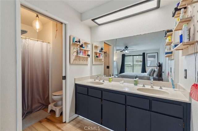 1045 Clover Ln, Hanford, CA 93230 - bathroom with wood finished floors, ensuite bath, ceiling fan, double vanity, and toilet