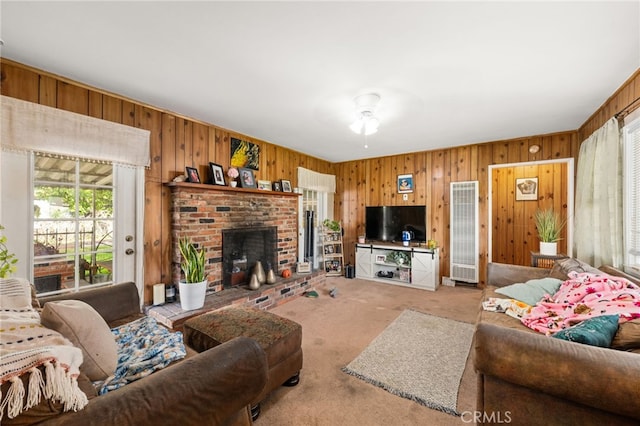 carpeted living room with a heating unit, wood walls, and a fireplace