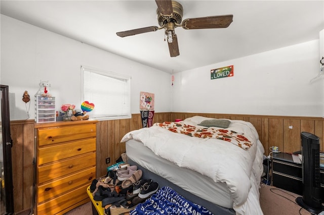 bedroom with a wainscoted wall, ceiling fan, and wood walls