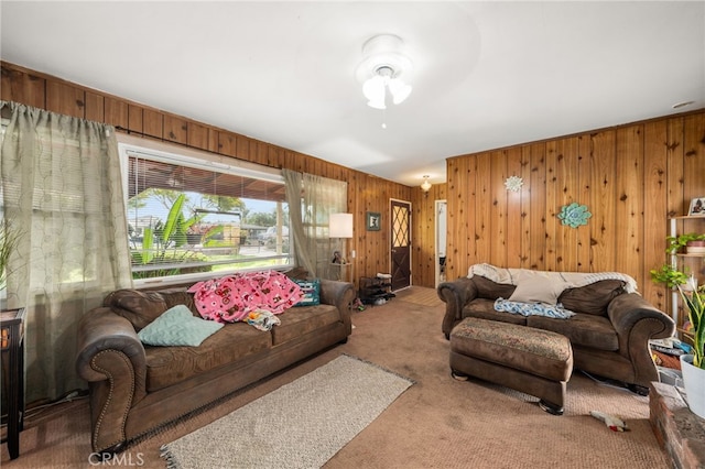 carpeted living room with wood walls and ceiling fan