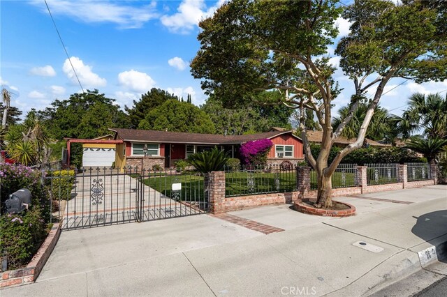 ranch-style home with a fenced front yard, driveway, an attached garage, and stone siding