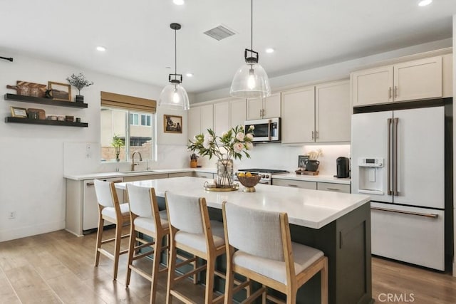 kitchen with a sink, light countertops, light wood-style floors, a breakfast bar, and white appliances