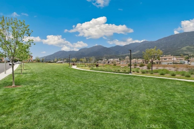 view of community with a lawn, fence, and a mountain view
