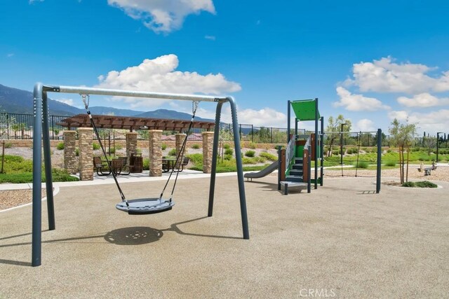 community playground featuring a mountain view and fence