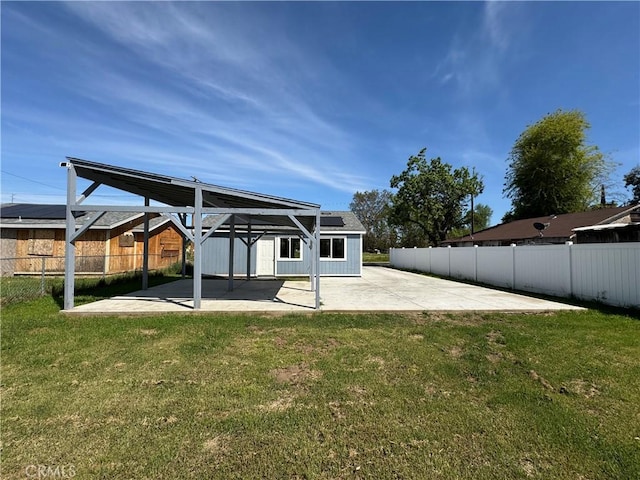 back of property with a lawn, a fenced backyard, a patio area, and roof mounted solar panels