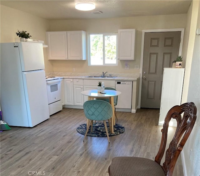kitchen with white appliances, white cabinets, light wood-style flooring, and light countertops