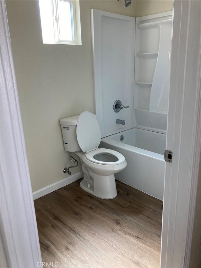 full bathroom with baseboards, toilet, wood finished floors, and tub / shower combination